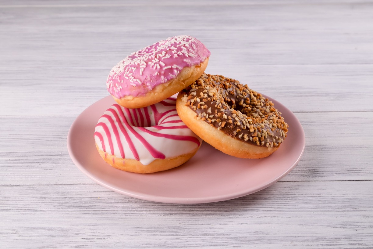 tres donuts de chocolate y color rosa en un plato con coberturas deliciosas
